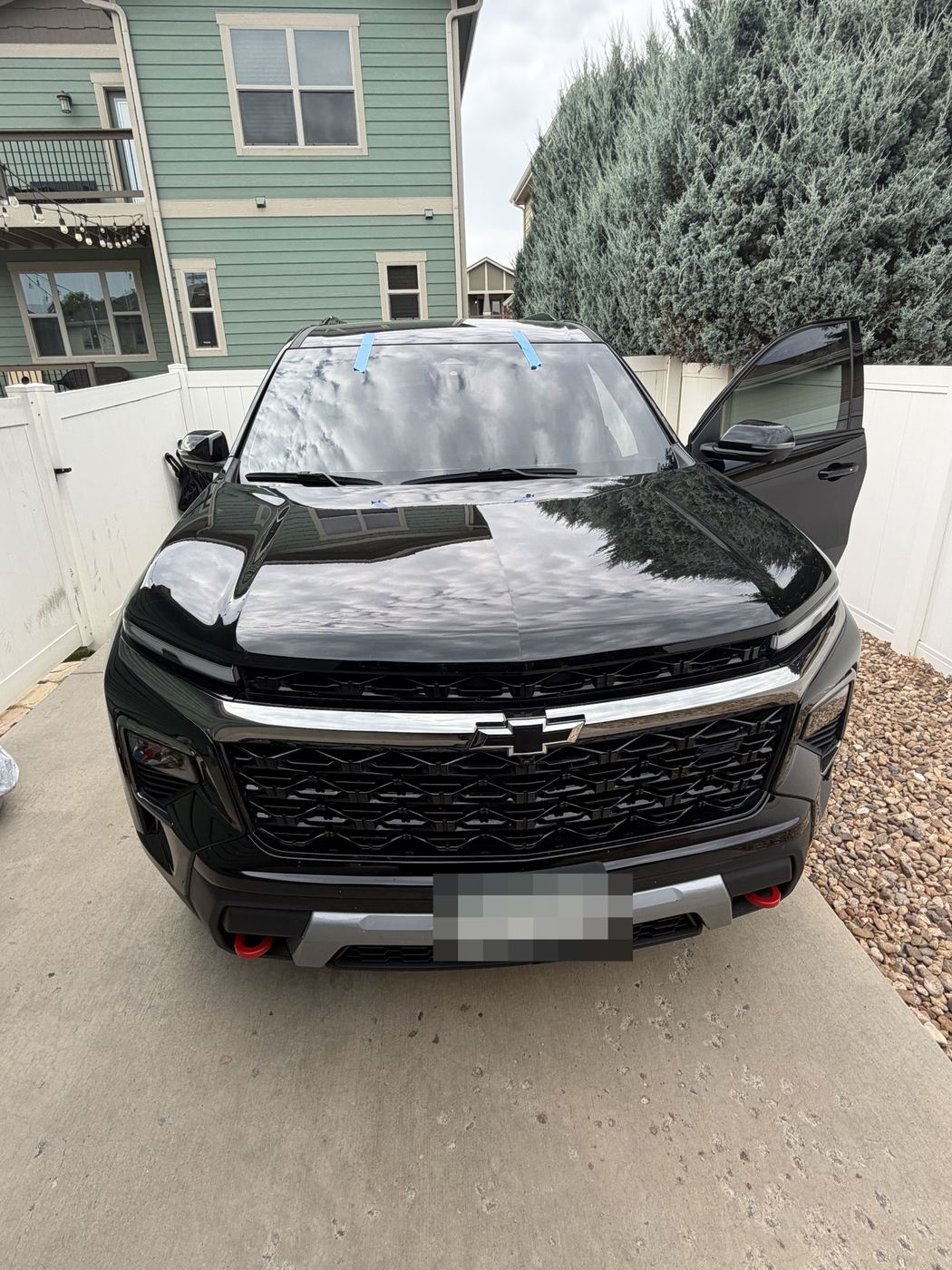Newly installed windshield taped and curing on an SUV in a residential driveway