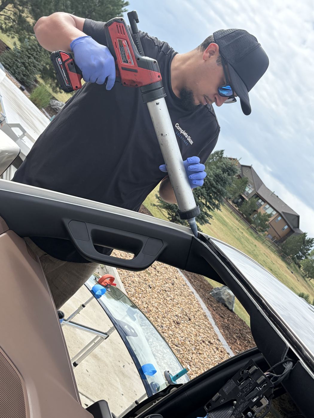 Technician applying a urethane bead during a mobile windshield replacement